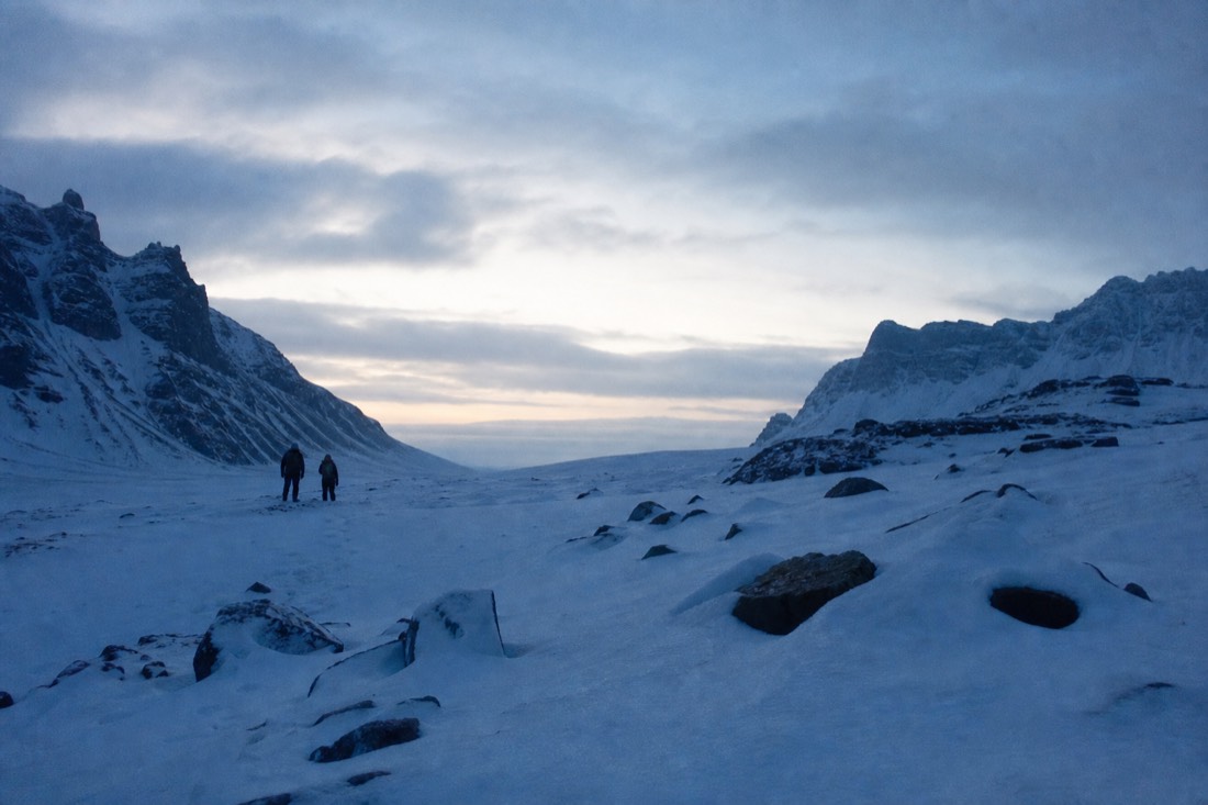 Snow drifted over an unploughed mountain pass at dusk, no tracks, dark peaks against pale sky