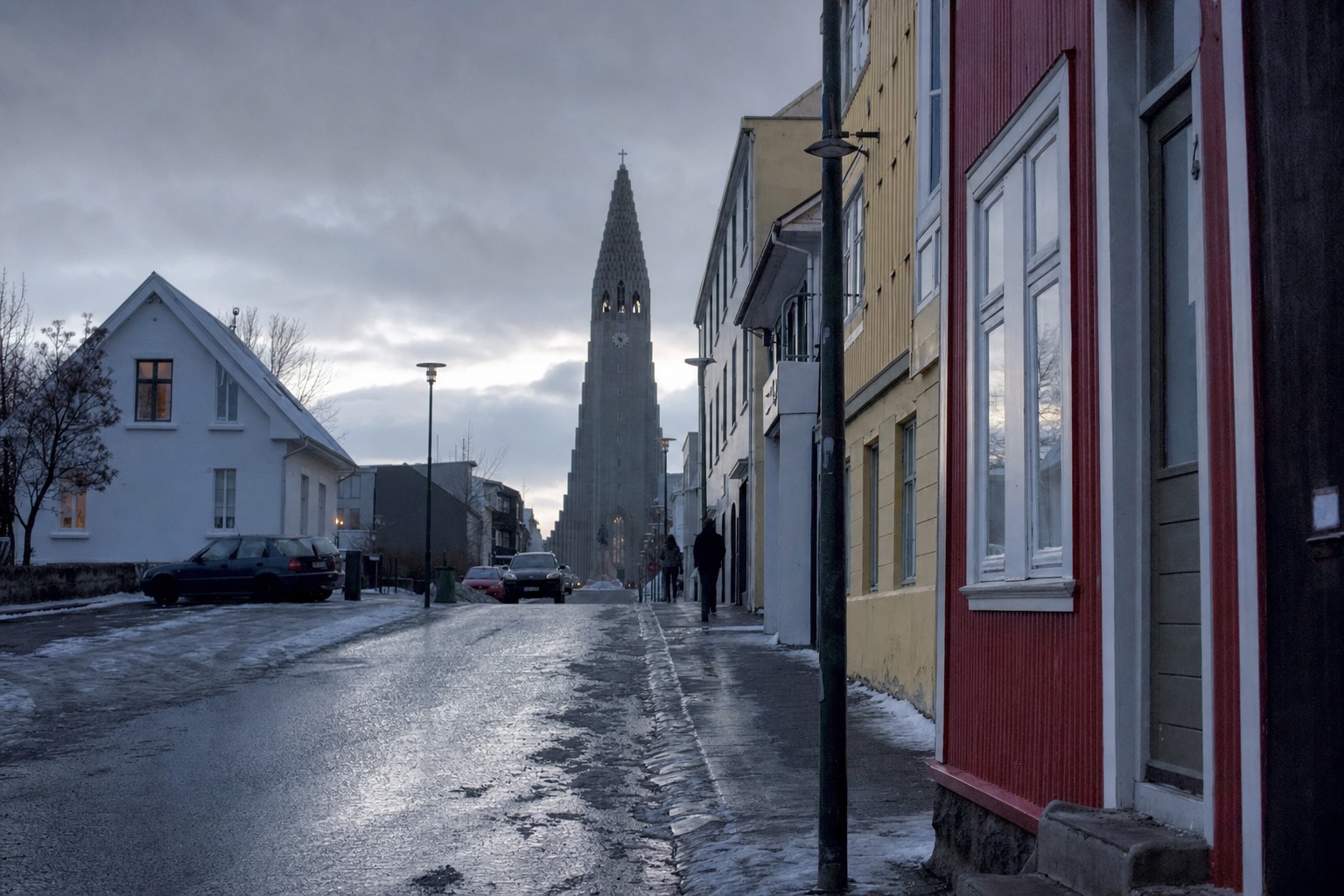 Rain-slicked Reykjavík street with coloured houses and Hallgrímskirkja under a dark winter sky