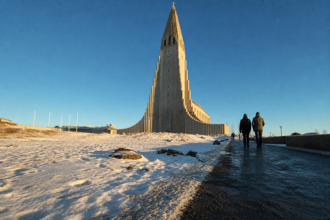 Golden low midday sun on Hallgrimskirkja's concrete facade against a deep blue sky