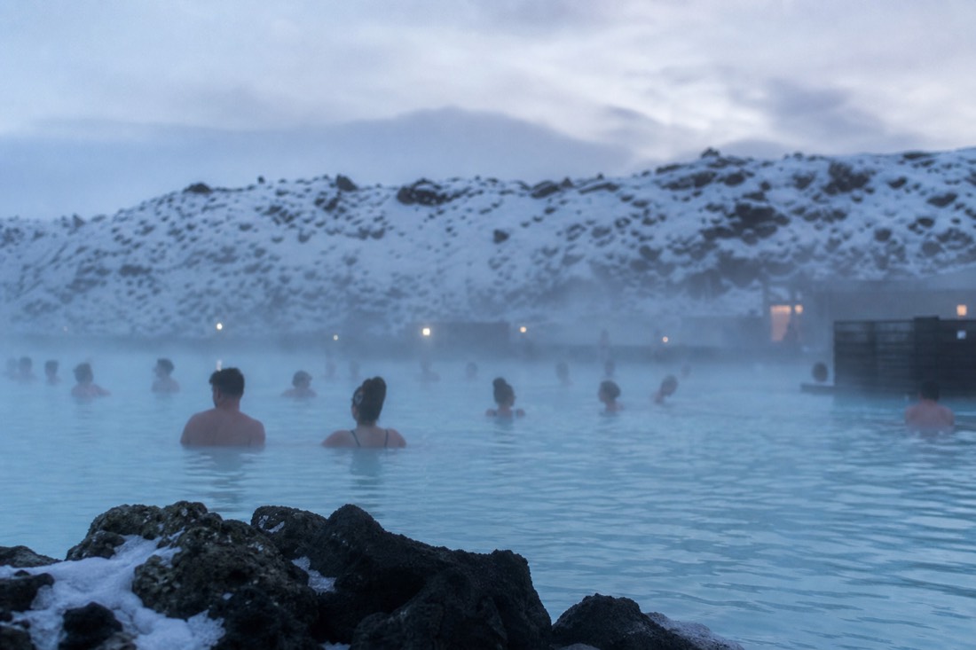 Bathers in the pale blue geothermal water of the Blue Lagoon on a winter afternoon