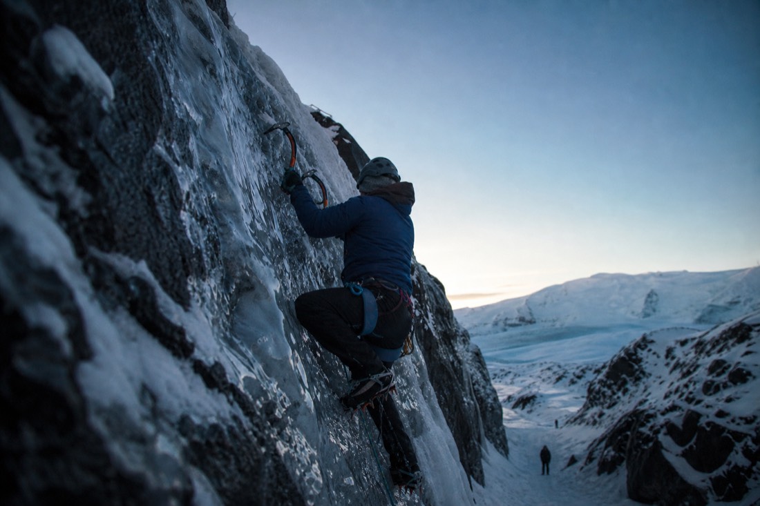 A climber on a short ice wall during an ice climbing intro on Sólheimajökull glacier
