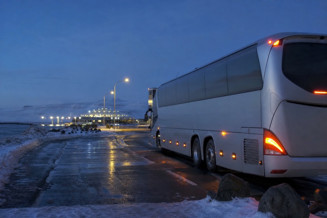 A large aurora coach waiting at a Reykjavík terminal on a winter evening