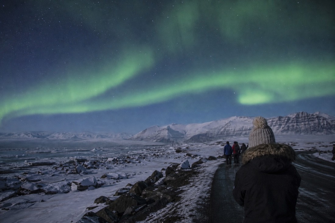 Travellers watching the aurora from a roadside stop on a northern lights tour from Reykjavík
