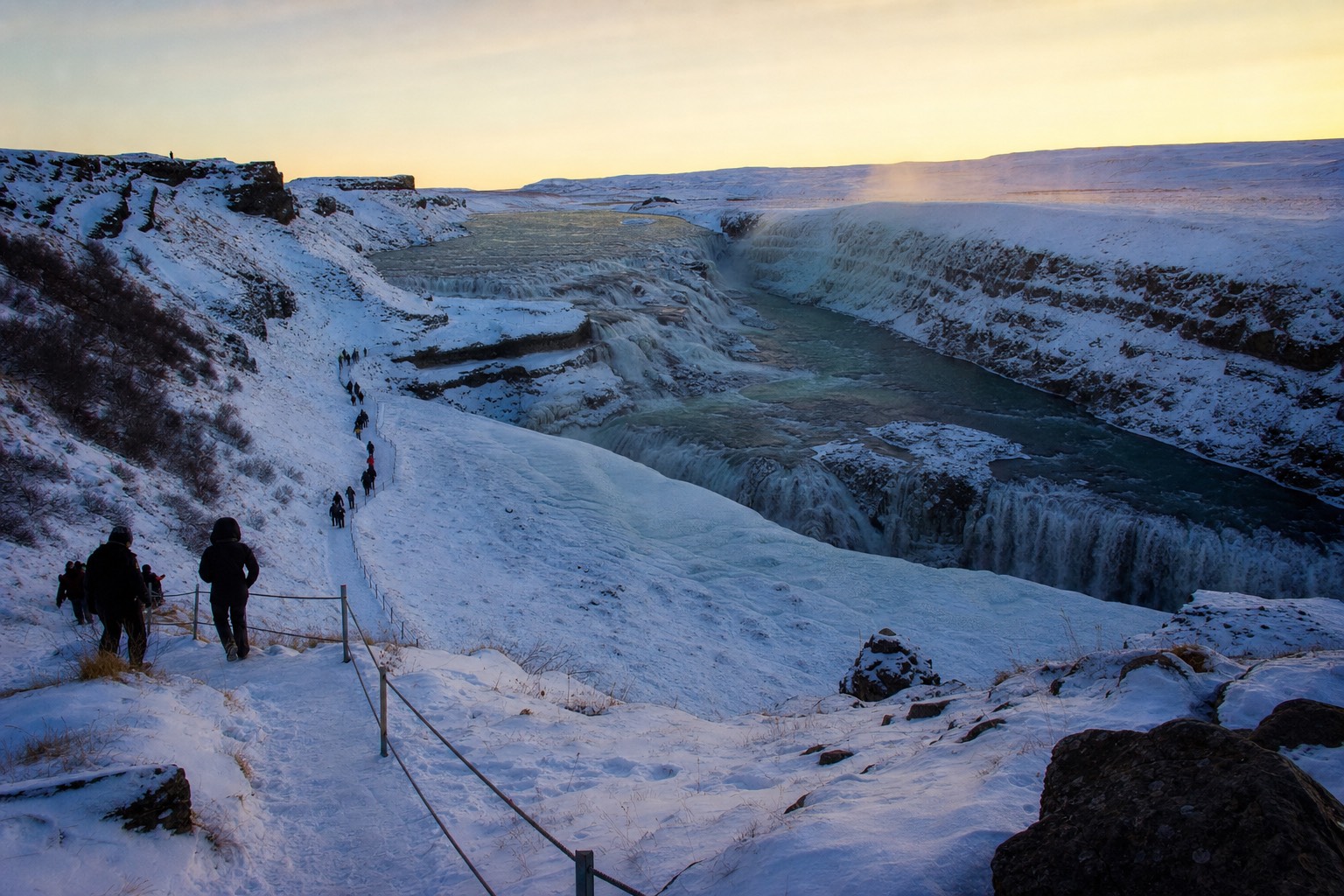 Gullfoss waterfall under snow and low winter sun on a Golden Circle tour from Reykjavík