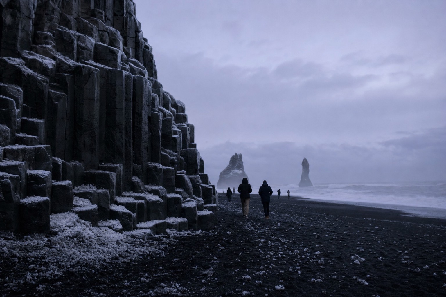 The black sand and basalt columns of Reynisfjara beach under winter cloud on a South Coast tour