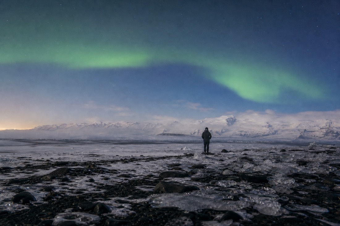 Faint green aurora arc over a snowy field far from town on a clear cold night