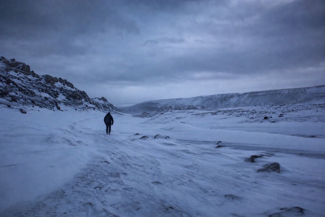 Drifted snow burying an unpaved interior track in Iceland under a heavy grey sky