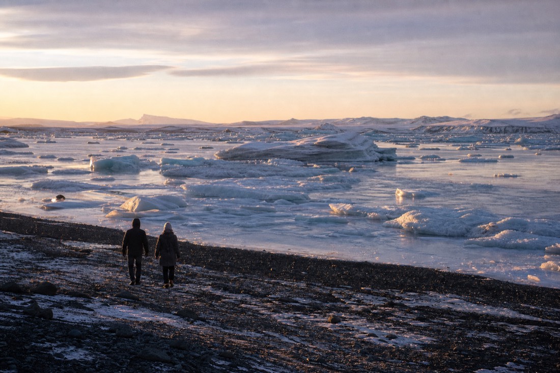 Low January sun on the icebergs at Jokulsarlon with a frozen black shoreline