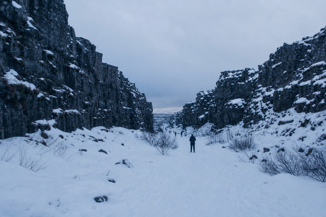 Flat overcast light on Thingvellir under snow, grey rift walls and low cloud pressing down