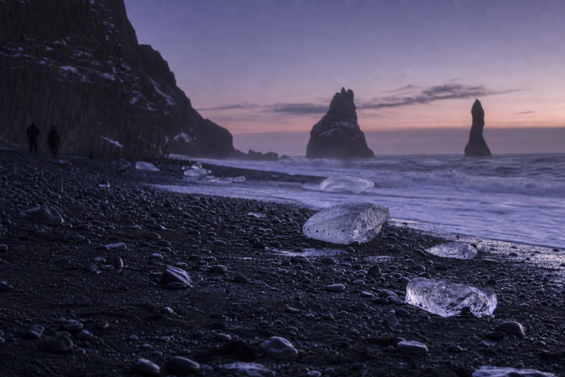 Reynisfjara black sand under violet fading twilight, sea stacks dark against the last colour