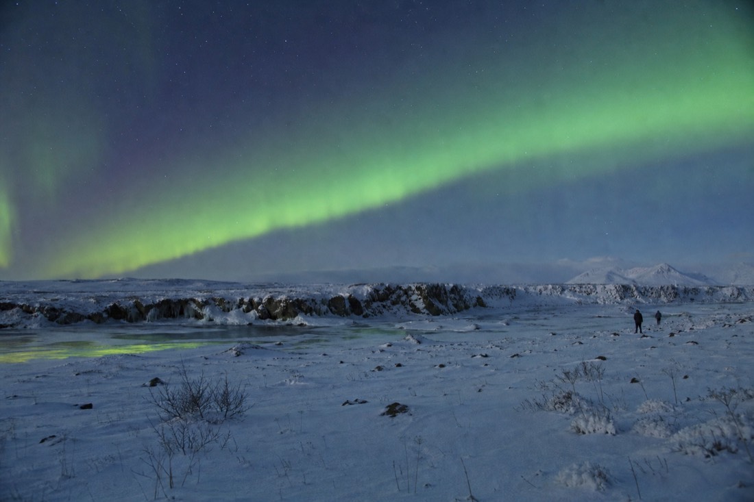 December aurora arc over a snow-covered field outside Reykjavik on a clear cold night