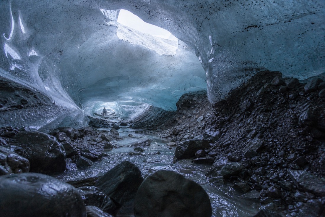 Daylight coming through a thinning ice cave roof in February, blue walls and a wet floor
