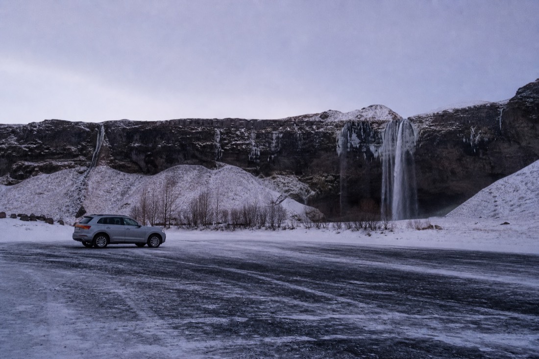 Empty snow-packed car park at Seljalandsfoss in January, one vehicle and nobody about