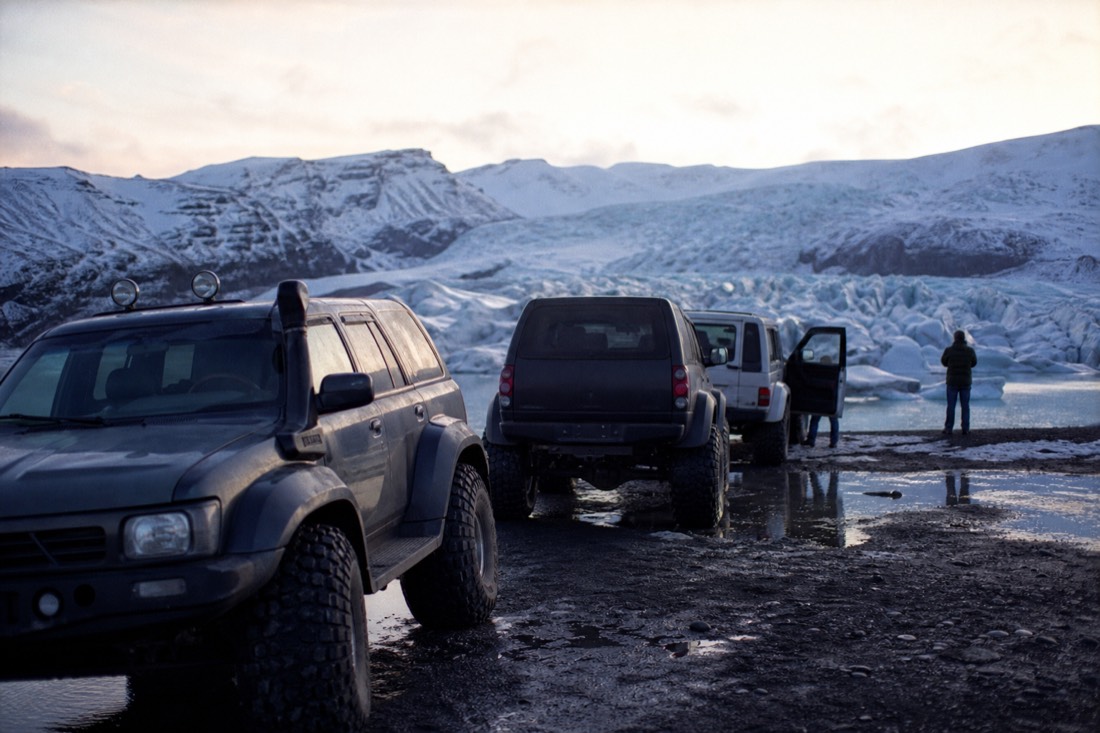 Super jeeps waiting at the Jokulsarlon meeting point in low January light, glacier behind