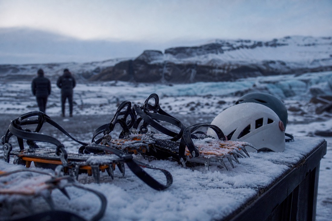 Crampons and helmets laid on a snowy tailgate at a glacier meeting point in morning twilight