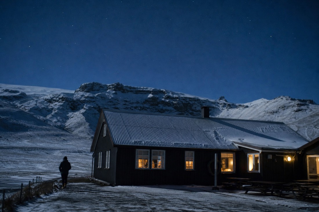 Clear cold night above a small south Iceland guesthouse, snow on the roof and stars overhead