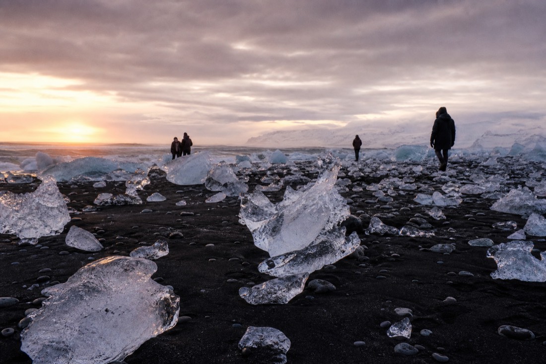 First light on Diamond Beach, glacier ice scattered across black sand under heavy grey sky
