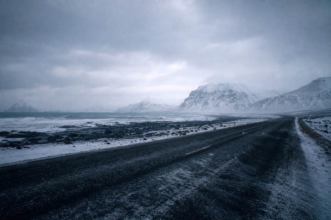 Empty snow-swept stretch of Route 1 in east Iceland under heavy overcast, no traffic at all