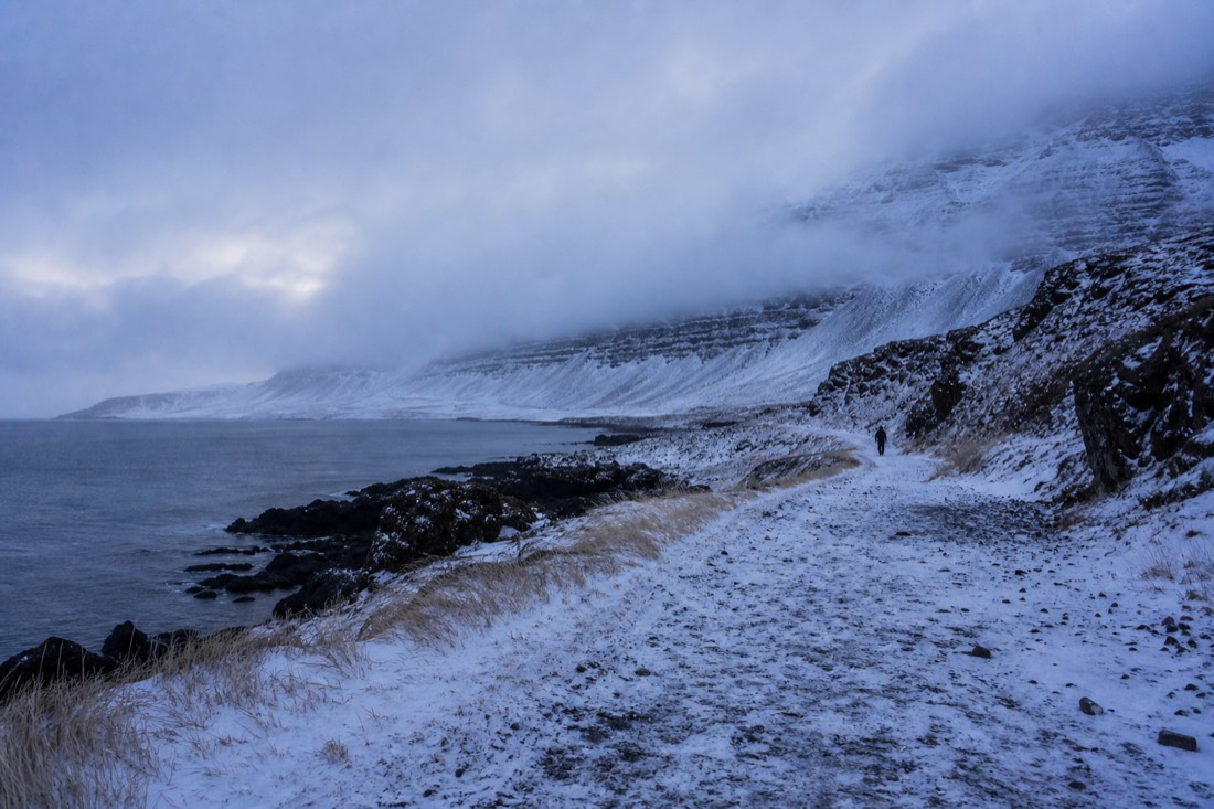 Snow-drifted unpaved spur on the Snaefellsnes peninsula with the pass clouded in behind