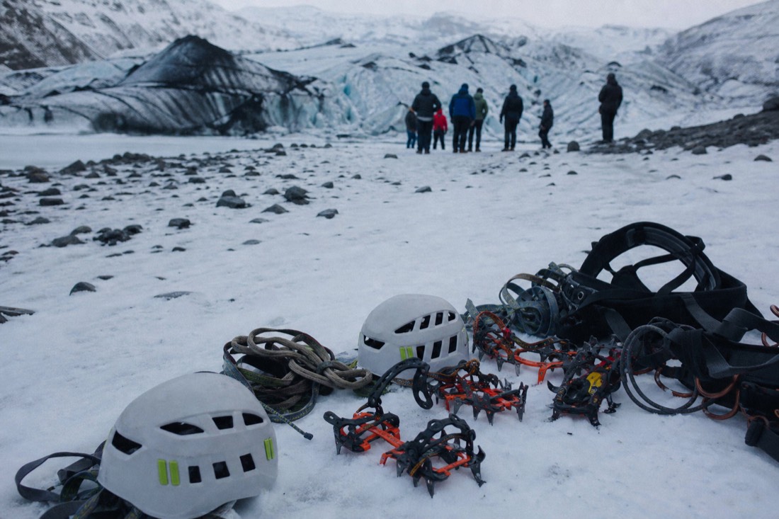 Helmets, harnesses and crampons laid out on packed snow at a glacier meeting point