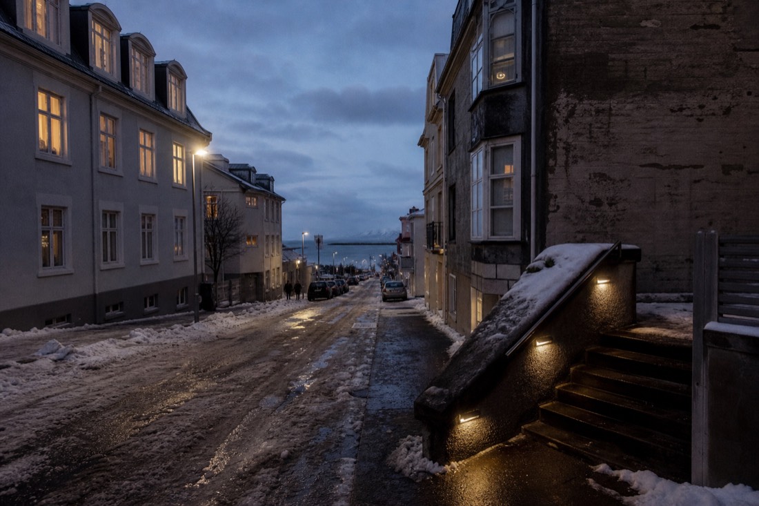 Reykjavik side street on a winter evening, hotel windows lit and wet snow on the road