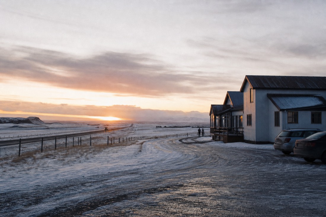 Low winter sun on a farm guesthouse near Hvolsvollur, snowy fields and Route 1 running past