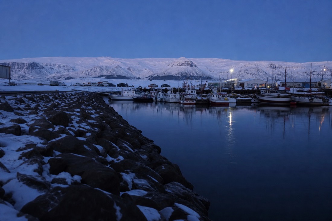 Hofn harbour on a clear cold winter night, Vatnajokull white along the horizon behind